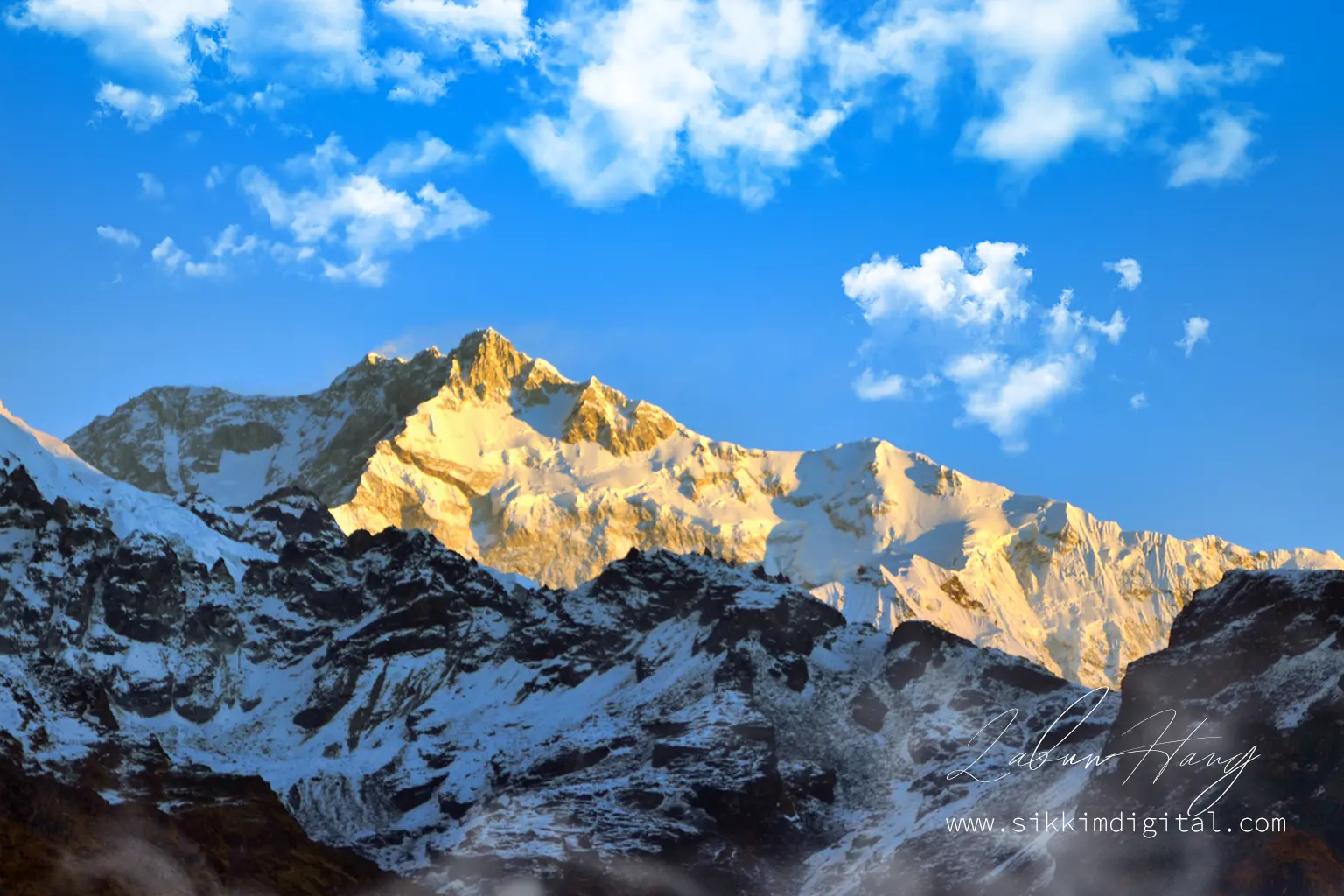 Golden sunrise over Mount Kanchenjunga viewed from Dzongri Top in Sikkim, with pristine snowfields and rugged ridgelines glowing under a brilliant Himalayan sky.